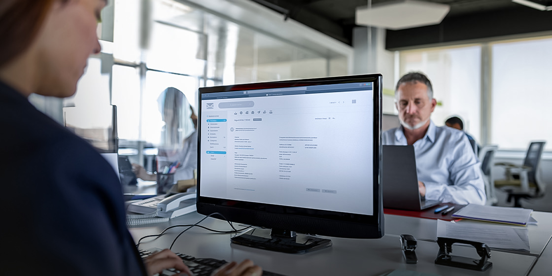 A photo showing employees working in front of a computer.