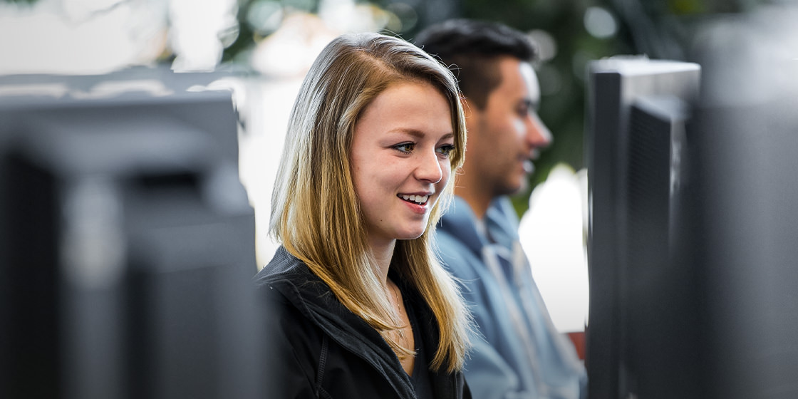The image shows two co-workers using invoice process automation software in an office environment.