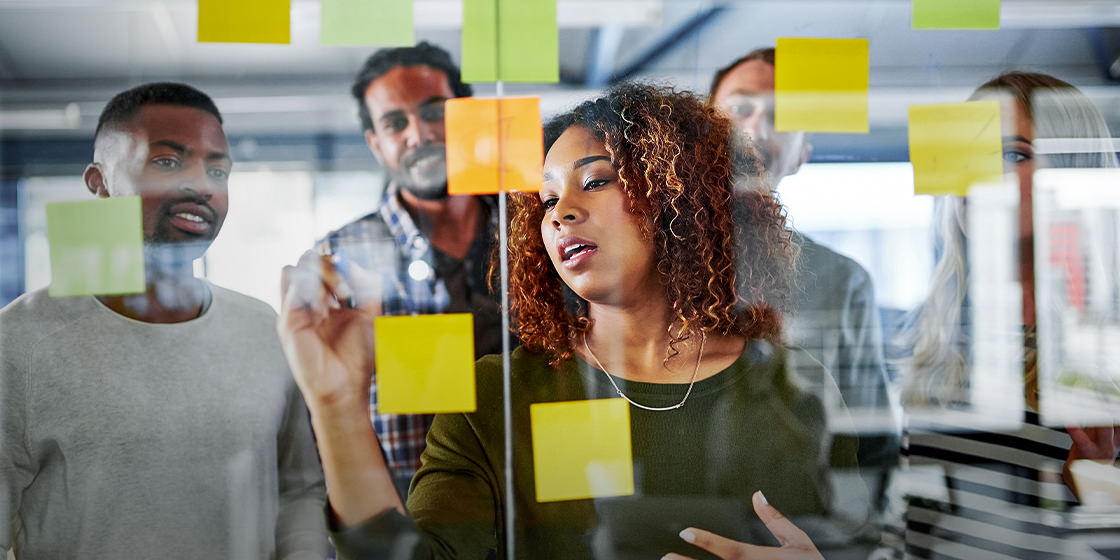 The image shows a woman and her co-workers in a professional office environment carefully planning out an automation strategy that incorporates intelligent document processing (IDP).